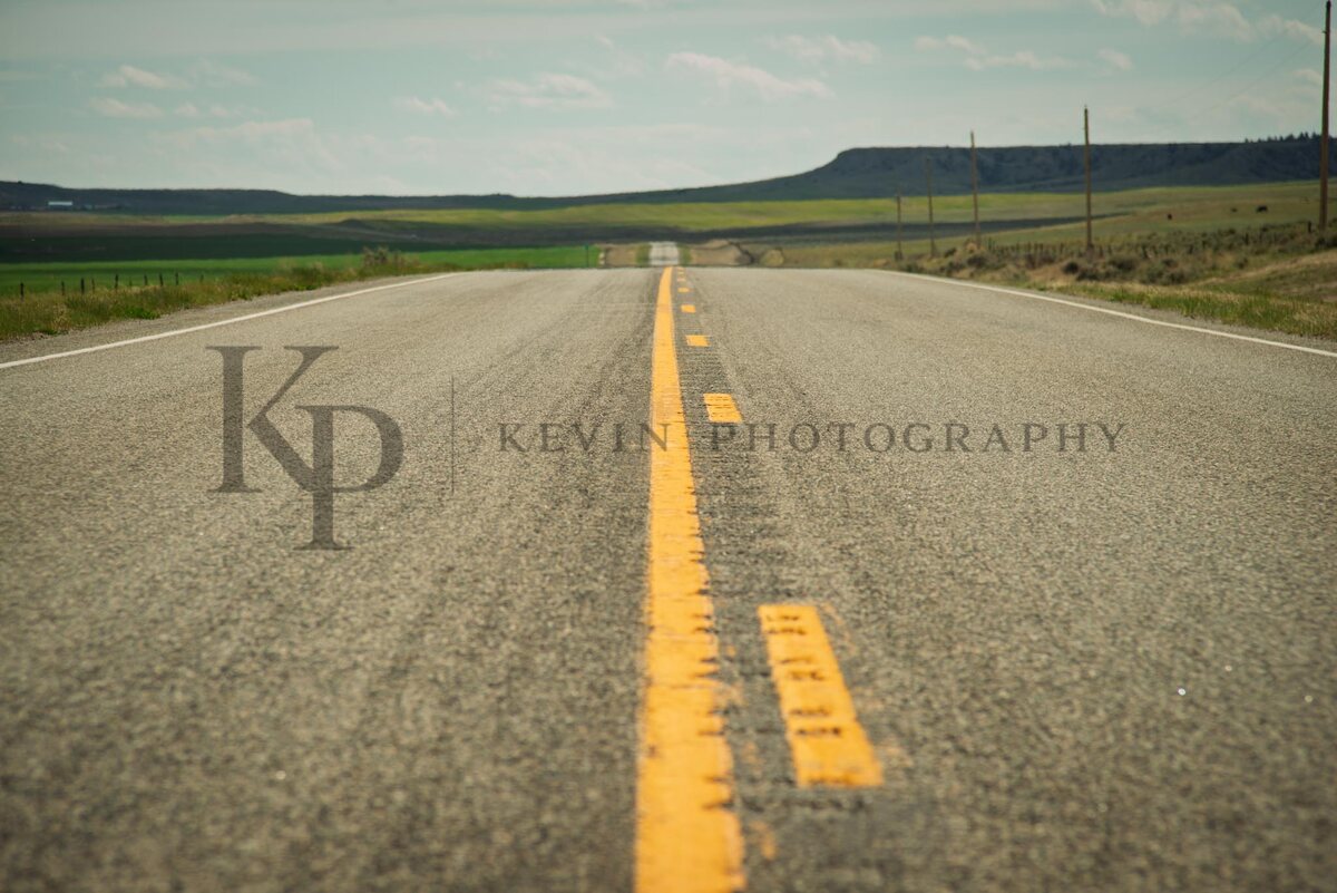 A straight Montana road cutting through open range toward the horizon.